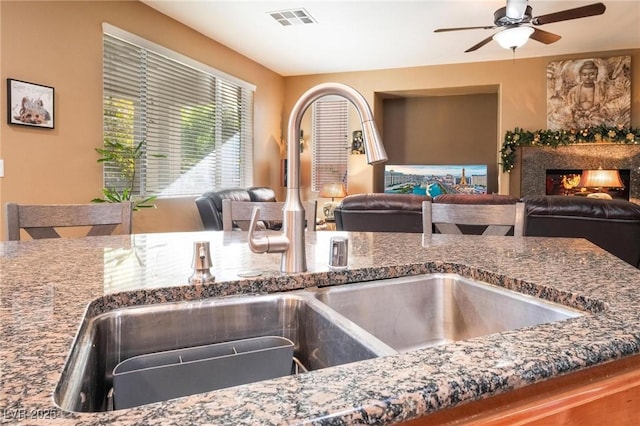 kitchen with sink, ceiling fan, and stone countertops