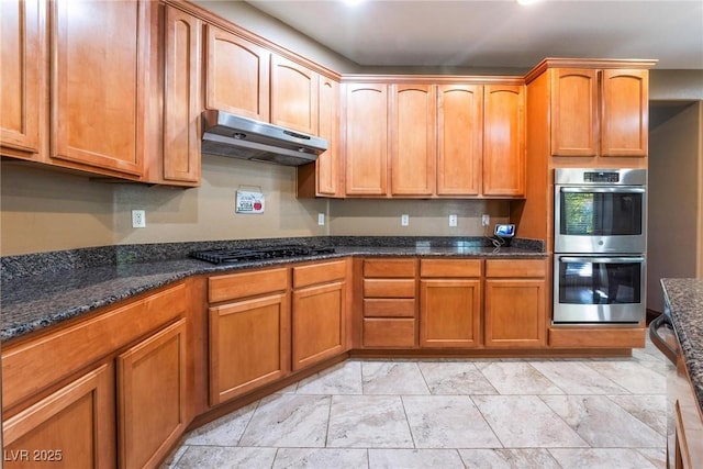 kitchen with stainless steel double oven, dark stone countertops, and black gas stovetop