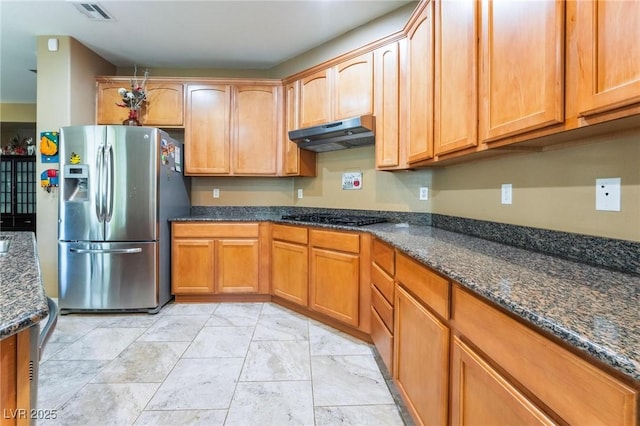 kitchen with dark stone counters, black gas stovetop, and stainless steel refrigerator with ice dispenser