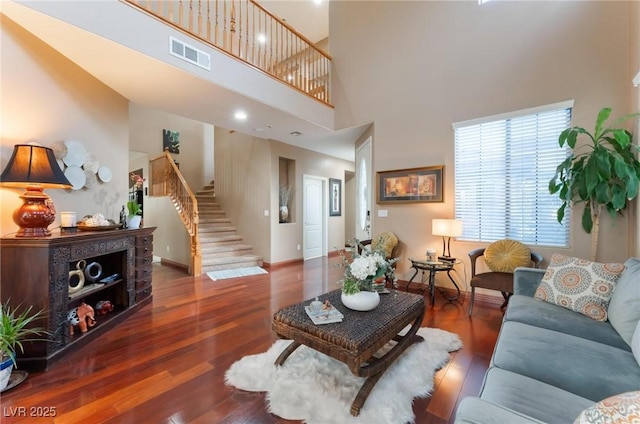 living room with a towering ceiling and dark wood-type flooring