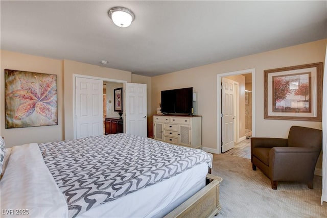 bedroom with ensuite bath and light colored carpet