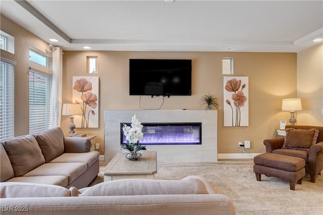 living room featuring a tile fireplace and a raised ceiling