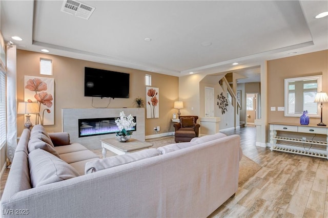 living room with a tile fireplace and light hardwood / wood-style flooring