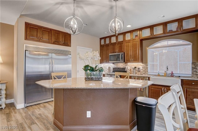 kitchen featuring a chandelier, decorative light fixtures, a kitchen island, appliances with stainless steel finishes, and sink