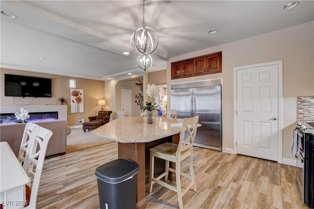 kitchen with light stone counters, a center island, decorative light fixtures, appliances with stainless steel finishes, and a kitchen breakfast bar