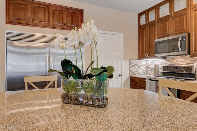 kitchen featuring tasteful backsplash, stainless steel appliances, and light stone countertops