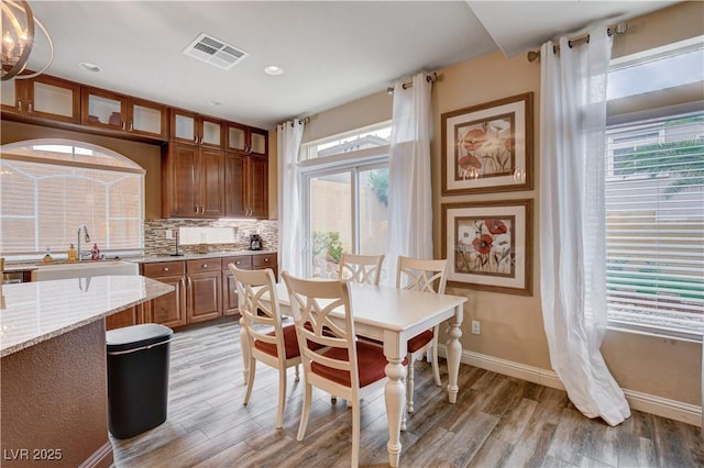 dining room featuring sink, light wood-type flooring, and a healthy amount of sunlight