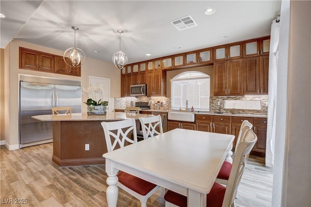 kitchen featuring stainless steel appliances, sink, decorative light fixtures, an inviting chandelier, and a kitchen island