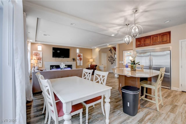 dining area with light wood-type flooring and an inviting chandelier