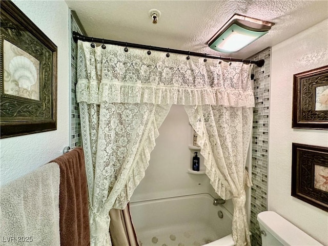 bathroom featuring a textured ceiling, shower / tub combo, and toilet