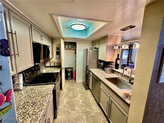 kitchen featuring appliances with stainless steel finishes, hanging light fixtures, a tray ceiling, sink, and light tile patterned flooring