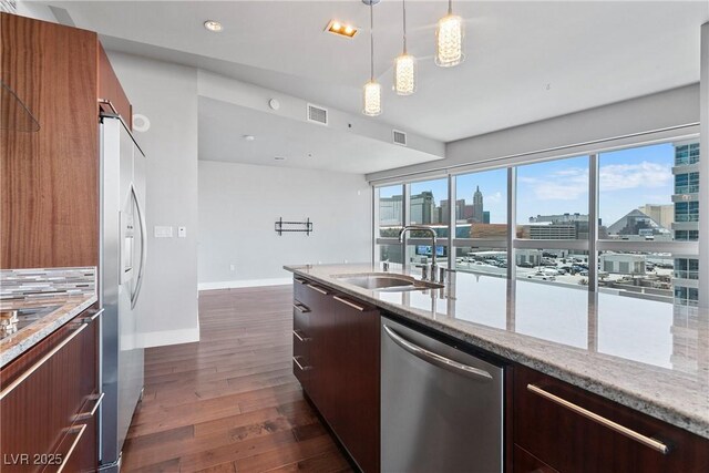 kitchen featuring light stone counters, hanging light fixtures, decorative backsplash, appliances with stainless steel finishes, and sink