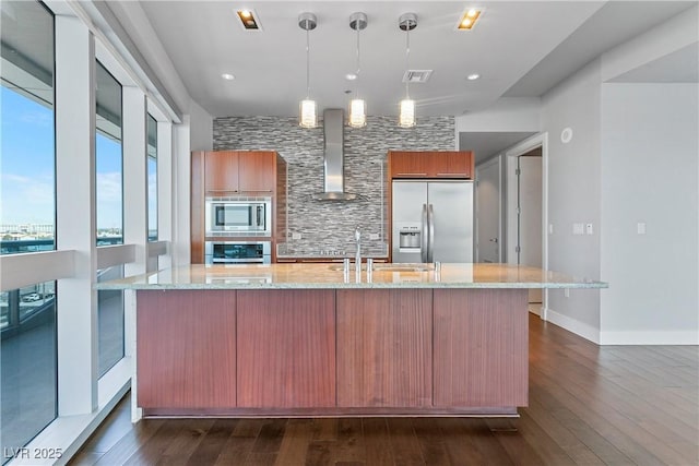 kitchen with built in appliances, pendant lighting, dark wood-type flooring, light stone counters, and wall chimney exhaust hood