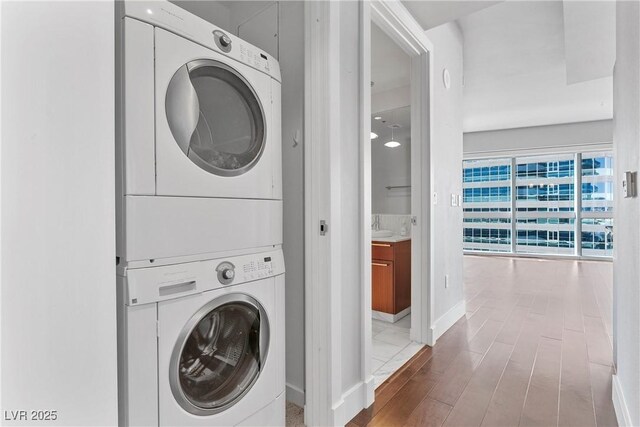 washroom with stacked washing maching and dryer and sink