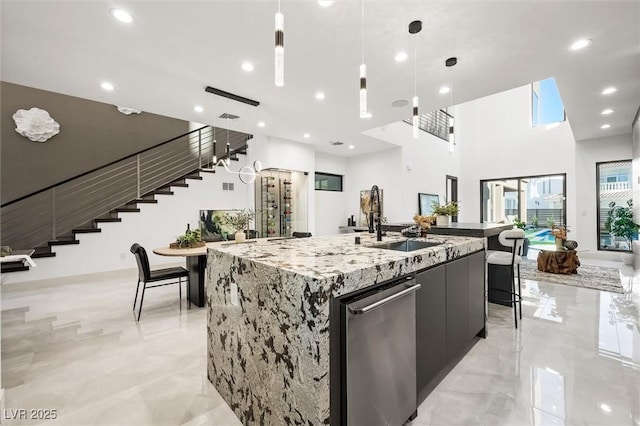 kitchen featuring stainless steel dishwasher, a large island, pendant lighting, and light stone counters