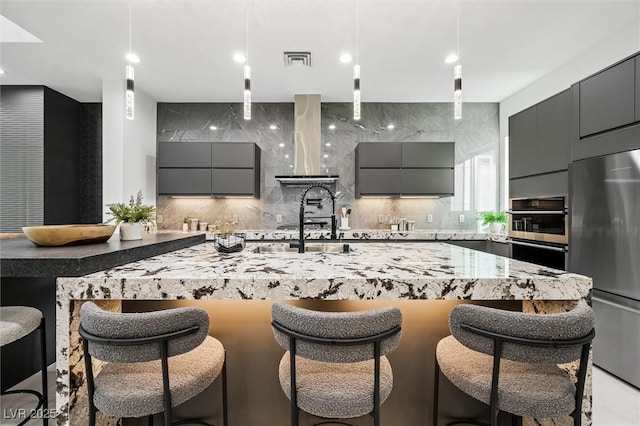 kitchen featuring stainless steel appliances, a breakfast bar, and gray cabinetry