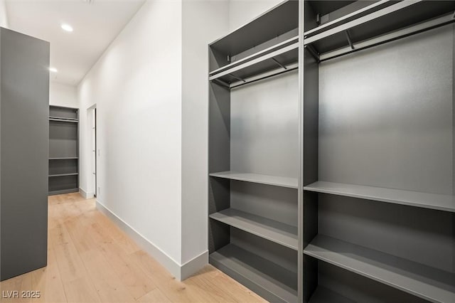 walk in closet with light hardwood / wood-style floors