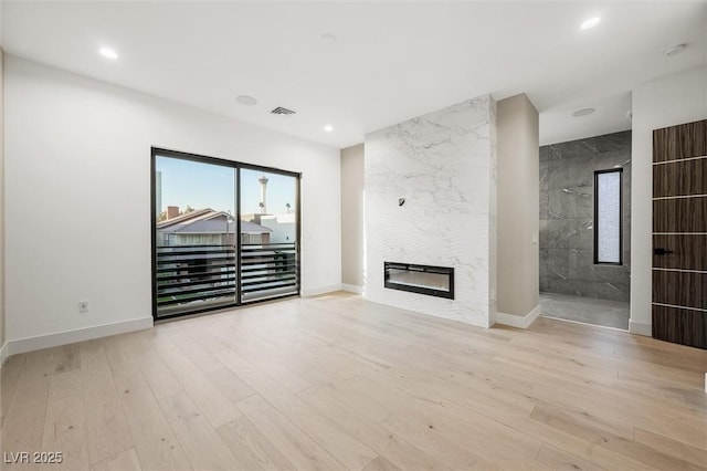 unfurnished living room with a large fireplace and light hardwood / wood-style floors