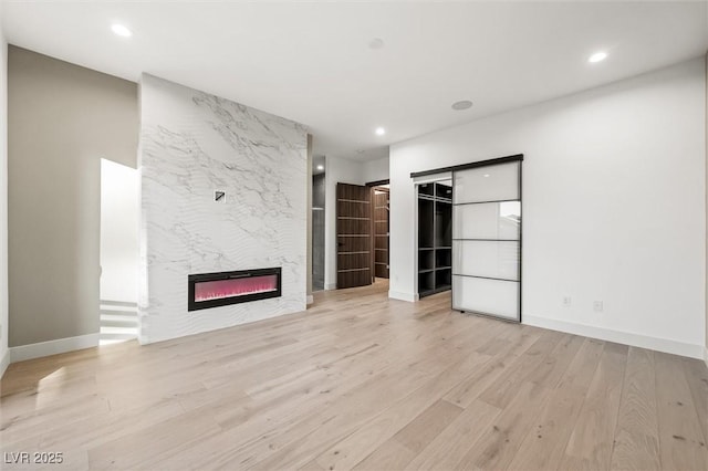 unfurnished living room featuring a large fireplace and light hardwood / wood-style floors