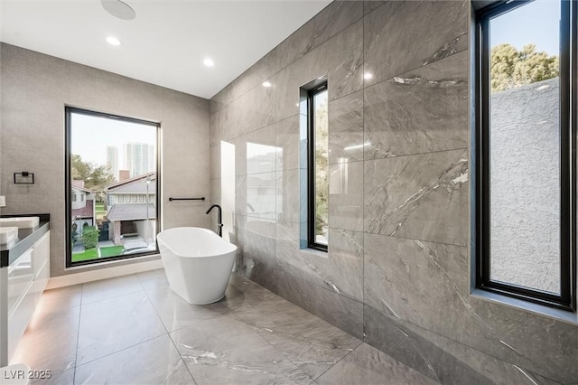 bathroom with tile walls, a bathtub, and a wealth of natural light