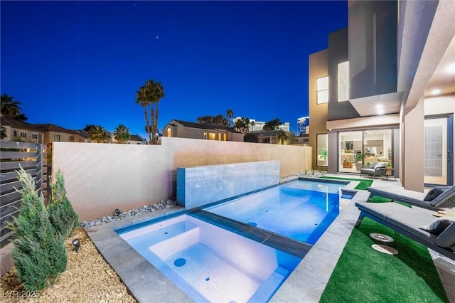 pool at twilight featuring a patio and an in ground hot tub