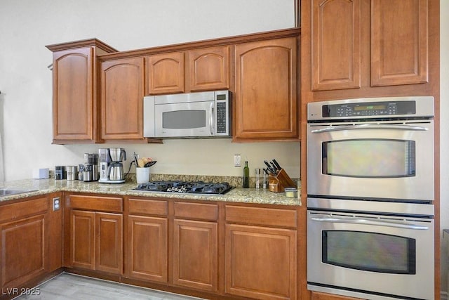 kitchen featuring light stone counters, appliances with stainless steel finishes, and sink