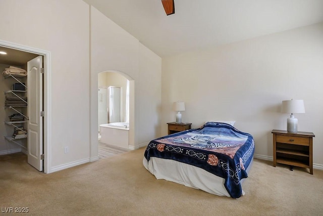 bedroom with ensuite bathroom, light colored carpet, high vaulted ceiling, a walk in closet, and ceiling fan