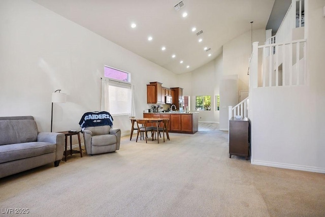 interior space featuring high vaulted ceiling, light colored carpet, and sink