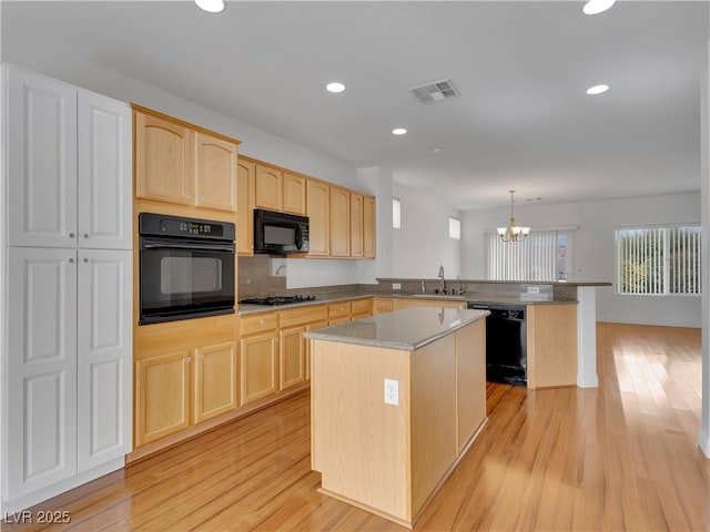 kitchen with pendant lighting, kitchen peninsula, light brown cabinetry, a kitchen island, and black appliances