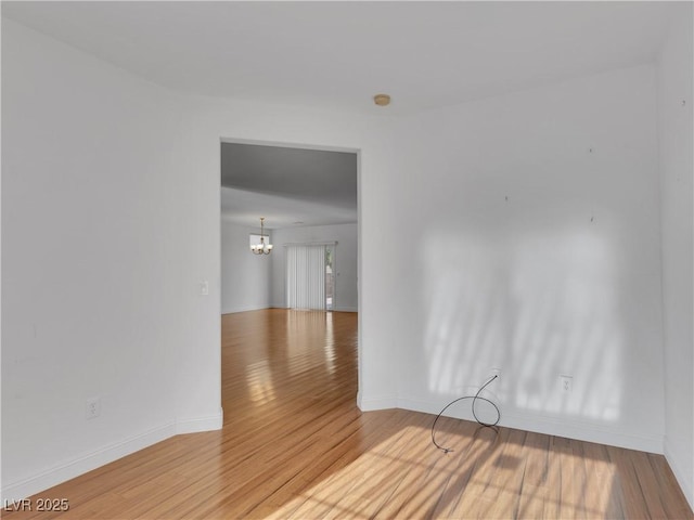 spare room with an inviting chandelier and wood-type flooring