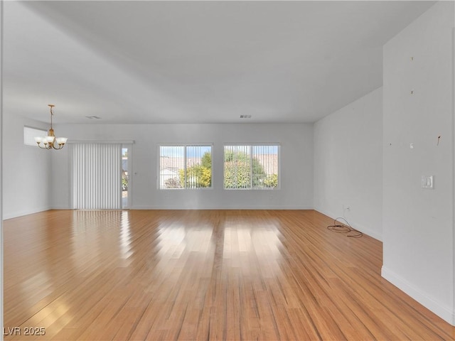 unfurnished room with light wood-type flooring and an inviting chandelier