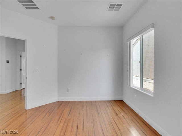 spare room featuring light wood-type flooring and plenty of natural light