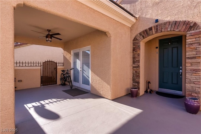 view of exterior entry featuring ceiling fan and a patio