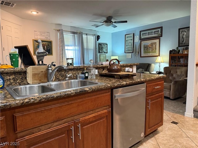 kitchen featuring ceiling fan, dark stone countertops, stainless steel dishwasher, sink, and light tile patterned floors