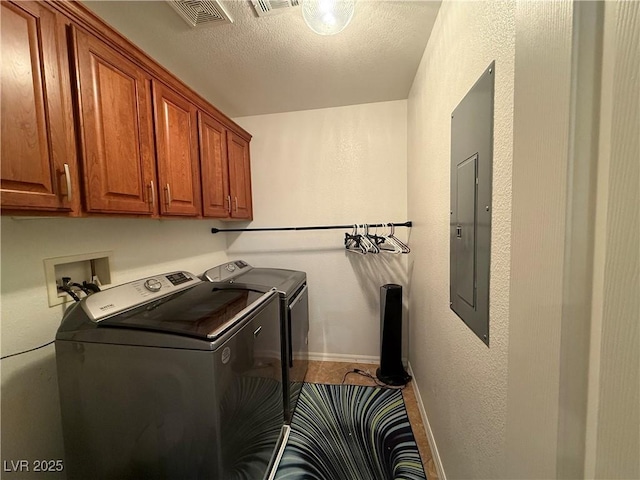 clothes washing area featuring a textured ceiling, cabinets, washer and dryer, and electric panel