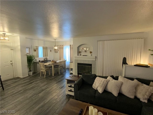 living room featuring a textured ceiling, a tiled fireplace, and dark hardwood / wood-style flooring