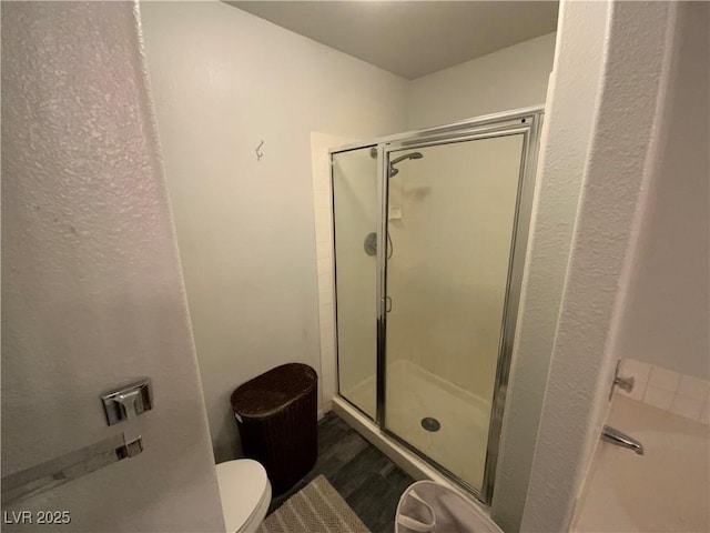 bathroom with toilet, hardwood / wood-style flooring, and a shower with shower door