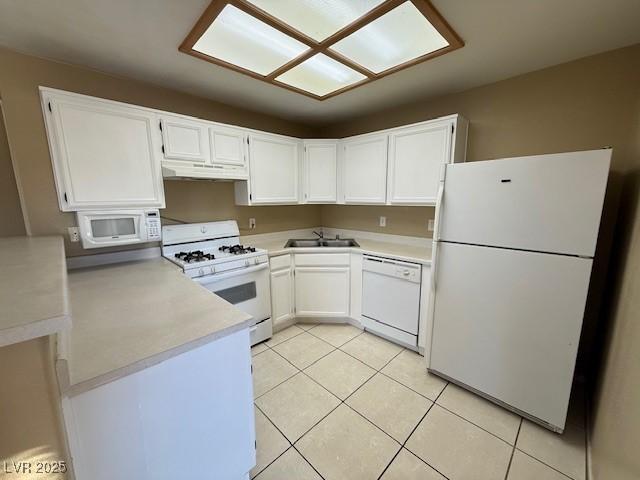 kitchen featuring white appliances, white cabinets, light tile patterned floors, and sink