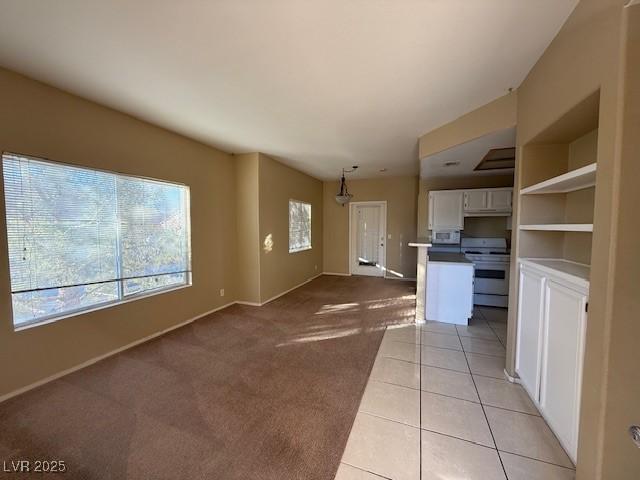 kitchen with decorative light fixtures, white cabinets, light carpet, and stove