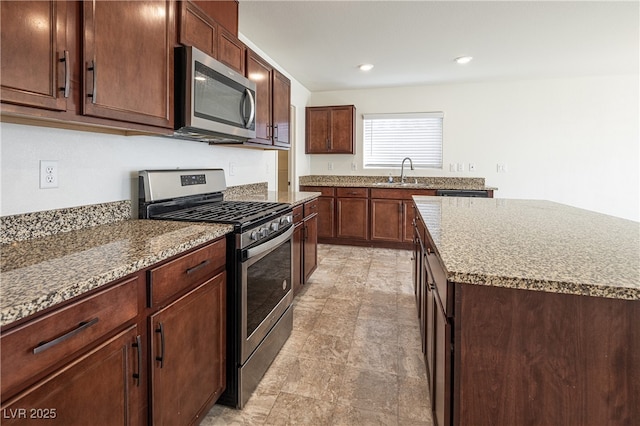 kitchen with stainless steel appliances, a center island, sink, and light stone counters