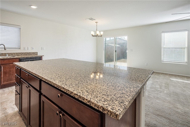 kitchen with sink, dark brown cabinets, hanging light fixtures, and a center island