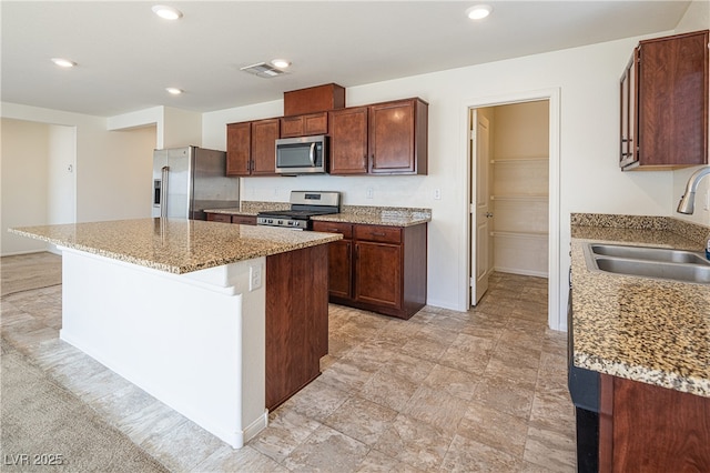 kitchen featuring stainless steel appliances, sink, a center island, light stone countertops, and light colored carpet