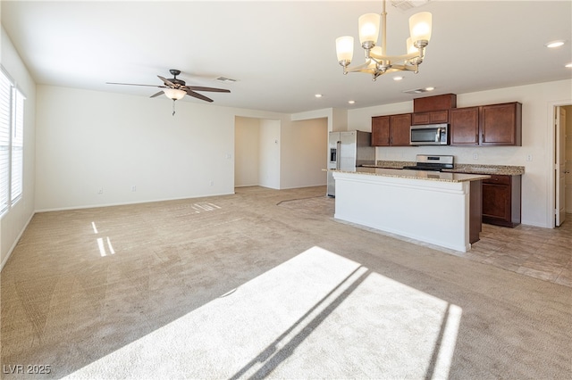 kitchen featuring appliances with stainless steel finishes, decorative light fixtures, a center island, ceiling fan with notable chandelier, and light colored carpet