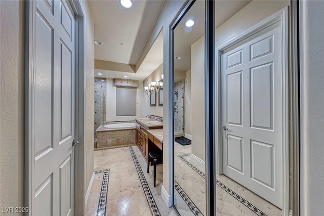 bathroom featuring vanity, tiled tub, and a notable chandelier