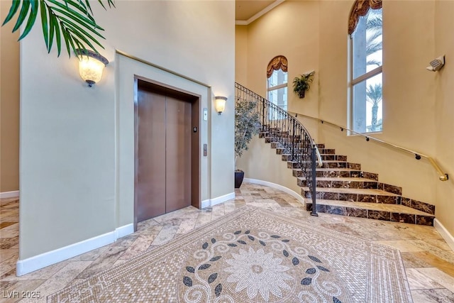 foyer featuring a high ceiling, elevator, and crown molding