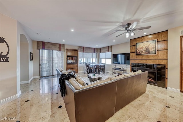 living room with a tiled fireplace and ceiling fan