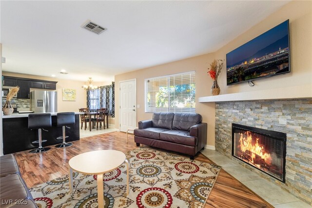 living room with a fireplace, an inviting chandelier, and light hardwood / wood-style floors