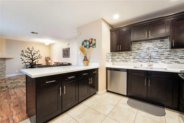 kitchen with sink, light tile patterned flooring, kitchen peninsula, stainless steel dishwasher, and dark brown cabinets