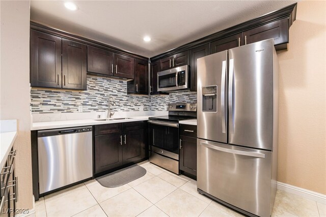 kitchen featuring stainless steel appliances, sink, light tile patterned floors, backsplash, and dark brown cabinetry