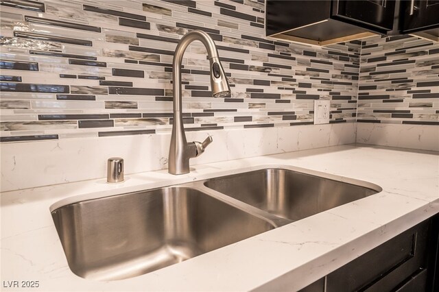 room details with light stone counters, decorative backsplash, and sink